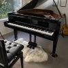 piano bench with back support in front of a piano