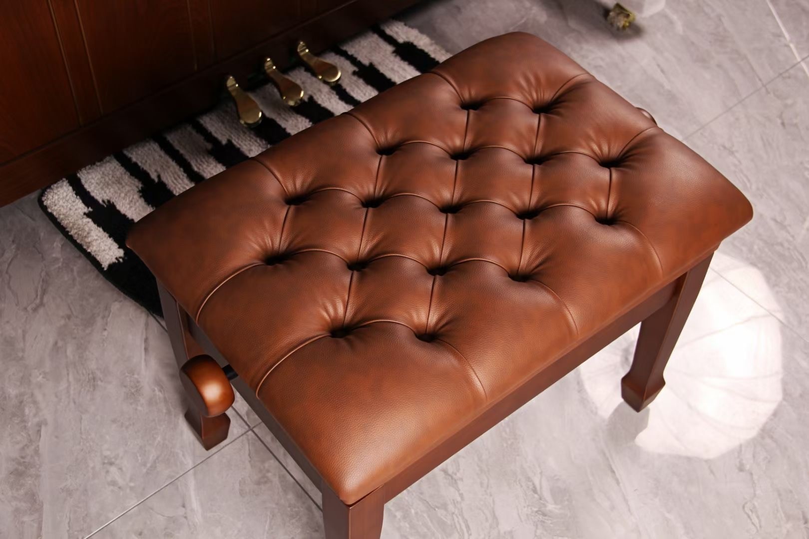 Walnut wood piano bench with tufted brown leather cushion in front of a piano
