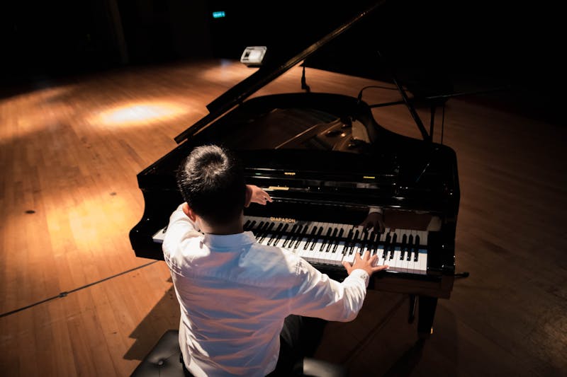 Pianist seated at a grand piano showing proper posture and seated position from behind