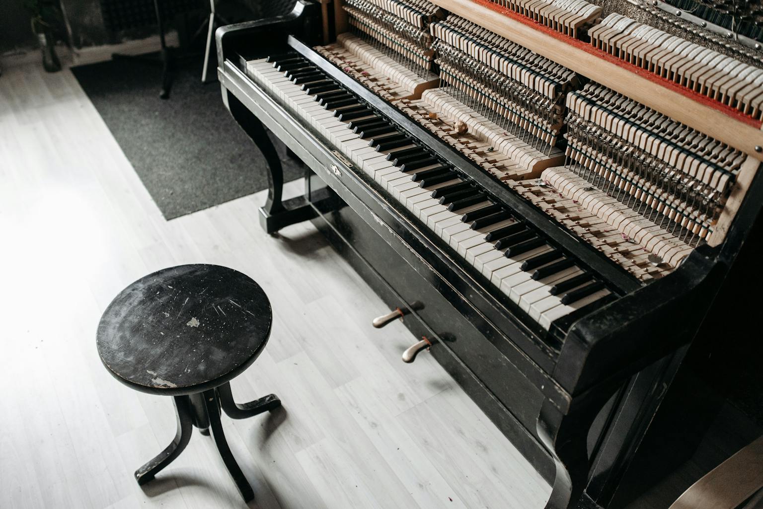 Round piano stool next to an open upright piano